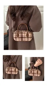 Detail view of plaid woolen boston bag with brown leather handles and gold metal hardware