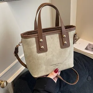 Retro khaki canvas bucket bag with brown leather handles and golden metal rivets