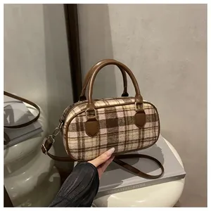 Detail of checkered tweed Boston bag with leather handles and gold metal hardware