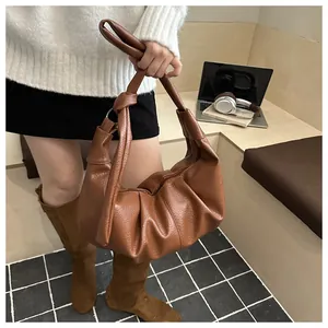 Detailed macro view of the brown lychee texture leather and knotted handle on hobo bag