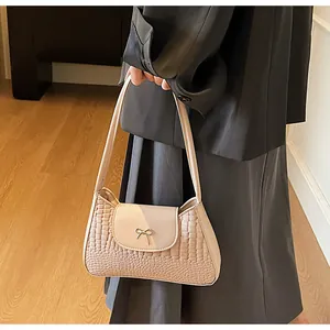 Detail of apricot crocodile pattern shoulder bag with a metallic bow clasp accent
