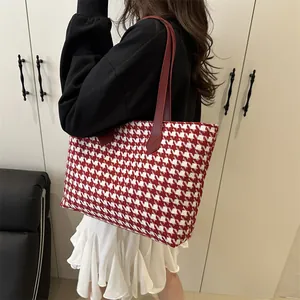 Classic red houndstooth tote bag with leather handles shown in a lifestyle shoulder view
