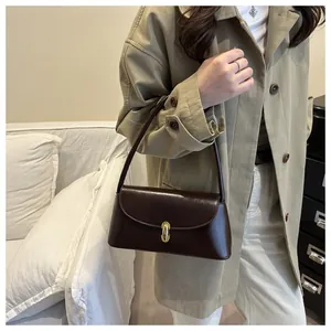 Detailed view of the dark brown glossy baguette bag with a premium golden metal clasp