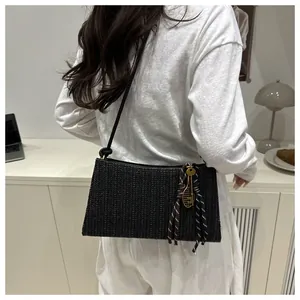 Detail of black woven shoulder bag with unique tennis racket charm and knot strap