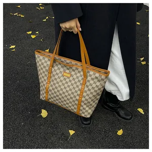 Macro view of large checkered tote bag showing brown leather handles and brand label