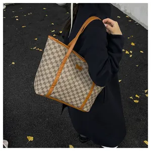 Detail of printed tote bag with leather straps worn by model in an outdoor autumn setting
