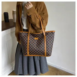 Detailed close-up of a brown checkered tote bag with leather handles on a cafe table