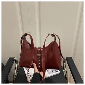 Detail of burgundy patent leather handbag featuring silver studs and buckle straps