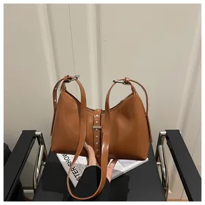 Detail view of brown vintage tote bag with silver studs and decorative leather strap