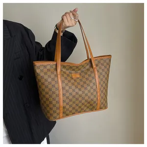 Detailed close-up of a large checkered tote bag with brown leather straps and trim