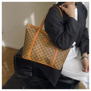 Detail of a large monogram tote bag worn with a chic black blazer for a retro look