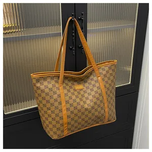 Detail of vintage checkered tote bag hanging on cabinet with elegant leather brand tag
