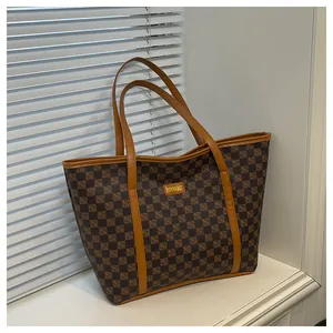Detail of printed large tote bag with brown checkered pattern and leather trim