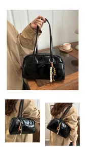 Detail of black glossy hobo bag with unique tricolor wooden bead charm and shoulder strap