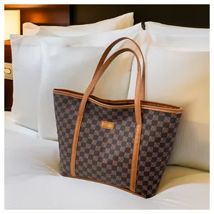 Detail of a brown checkered tote bag with a high-capacity design and leather strap accents