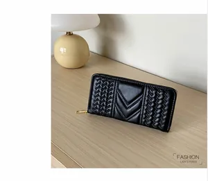 Detail of black quilted leather women's long wallet with golden zipper on wood surface