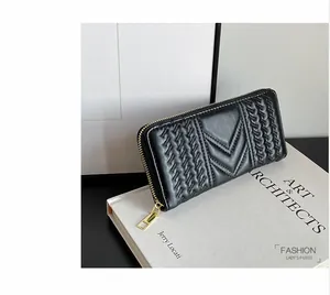 Detail view of black long wallet featuring V-shaped quilting and gold metal zipper