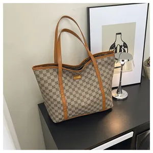 Detail of printed tote bag with leather handles and logo plaque on a black console