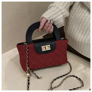 Close-up of wine red quilted texture bag with gold twist lock and woven chain strap