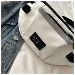 Close-up of white crossbody bag featuring reflective safety strip and black logo patch