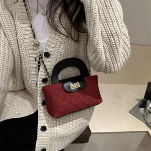 Burgundy quilted crossbody bag with black handle and gold chain strap shown on table