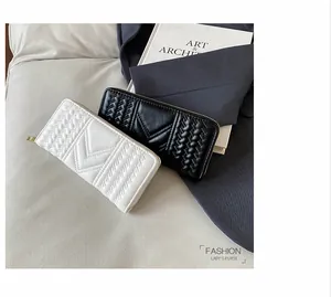 Detail of long women's purses in black and white with V-shaped quilting and golden zippers