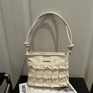 Chic beige lace underarm bag with tiered lace trim and gold logo detail on display