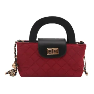 Quilted fabric red handbag with black top handle and elegant gold twist lock clasp