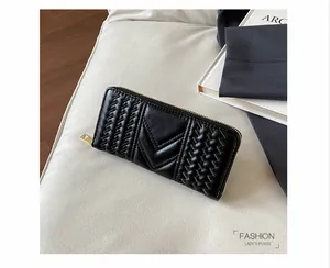 Detail view of a black quilted long wallet with V-pattern stitching and gold zipper