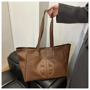 Close-up of the embossed HB logo and fine leather texture on this brown tote bag