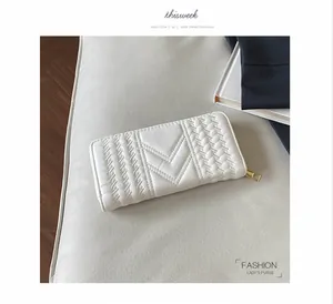 Detail of white long leather wallet featuring V-shape quilting and woven texture with zipper