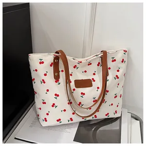 Detail der Canvas-Tasche mit Kirschprint, braunen Ledergriffen und Markenlogo-Patch