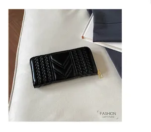 Detail of a black long clutch wallet with V-shaped quilted design and golden zipper hardware