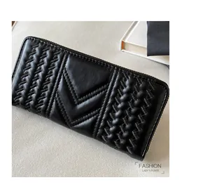 Detail of black quilted long wallet with V-shaped stitching and metal zipper hardware