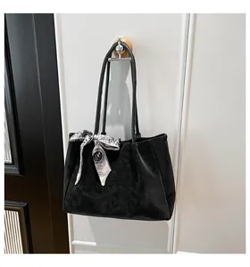 Detail of black suede tote bag with decorative printed scarf on the handle