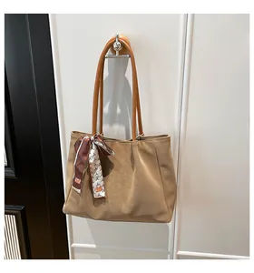 Detail of camel leather tote bag featuring a decorative silk scarf on the slim shoulder strap