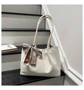 Detail of cream faux suede tote bag featuring decorative silk scarf on the handle