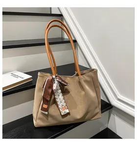 Detail of large beige suede tote bag with brown handles and a patterned silk scarf