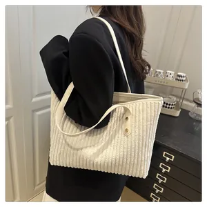 Detail of the white corduroy tote bag showing reinforced rivets and the leather shoulder strap