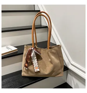 Close-up of khaki faux suede tote bag featuring lychee grain leather and decorative scarf