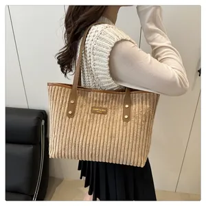 Detailed shot of khaki corduroy tote bag with brown leather handles worn by a model
