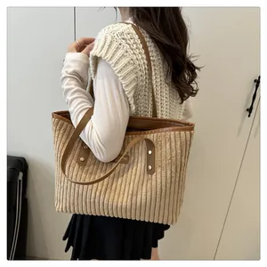 Detail of khaki corduroy tote bag featuring brown leather straps and metal rivets