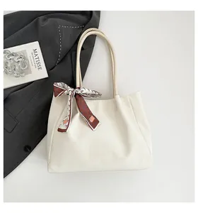 Detail view of a cream suede tote bag featuring a decorative printed silk scarf and slim straps