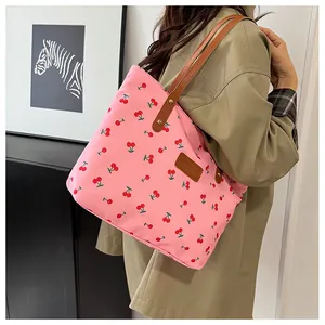 Detail of pink canvas tote bag with cherry print and leather logo label