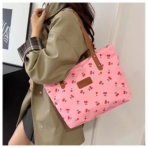 Gros plan sur un cabas rose en toile avec imprimé cerises et anses en cuir brun