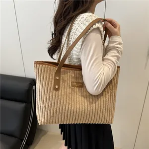 Fashionable corduroy tote bag with leather straps worn by model in a natural setting