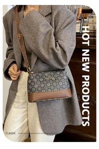 Detail of vintage printed crossbody bag with golden logo and textured shoulder strap