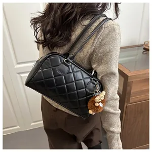 Rear view of model carrying black quilted shoulder bag with plush deer charm accessory