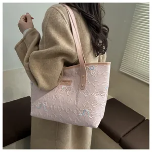 Sac cabas rose gaufré de lettres avec broderies nœuds porté sur un manteau de laine
