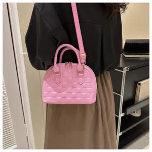 Detail showing pink shell bag with textured checkerboard embossing and top handles